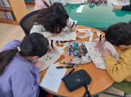 에코백에 그려진 스케치 위에 색칠을 하고 있는 어린이들