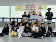 점프스타 줄넘기클럽 원생들과 박종국 원장(맨뒷줄 왼쪽 세번째)이 망포1동에 라면을 전달하며 기념촬영을 하고 있다