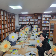 세류3동 새마을 문고 특성화프로그램에 참여한 이용자들이 자신들이 만든 자이언트 플라워를 들고 활짝 웃고 있다
