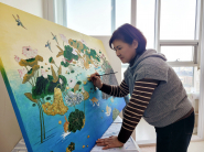 작업실에서 붓으로 연꽃과 연잎을 직접 그리고 있는 김순옥 작가. 자개를 붙이기 전 바탕이 되는 민화 채색 작업 장면이다.