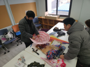 아이의 캠핑 의자에 사용하던 작은 우산의 수리 가능 여부를 살펴보고 있는 작업자들.