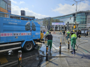 환경관리원들이 수원역 11번 출구 앞 도로를 고압세척기로 세척하고 있다.
