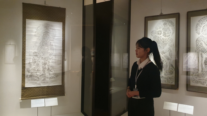 김송희 도슨트가 경주 단석산 신선사 마애미륵반가사유상 탁본(왼쪽 족자)과 사천왕상 탁본(오른쪽 액자)을 바라보며 전시를 점검하고 있다.
