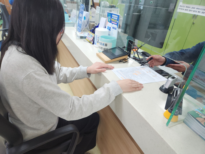 담당 공무원이 출산지원금 신청을 하러 온 산모에게 신청서 작성방법에 대해 설명해 주고 있다.