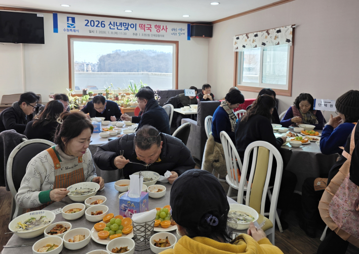 지역 단체와 직원이 함께 떡국을 먹고있다.