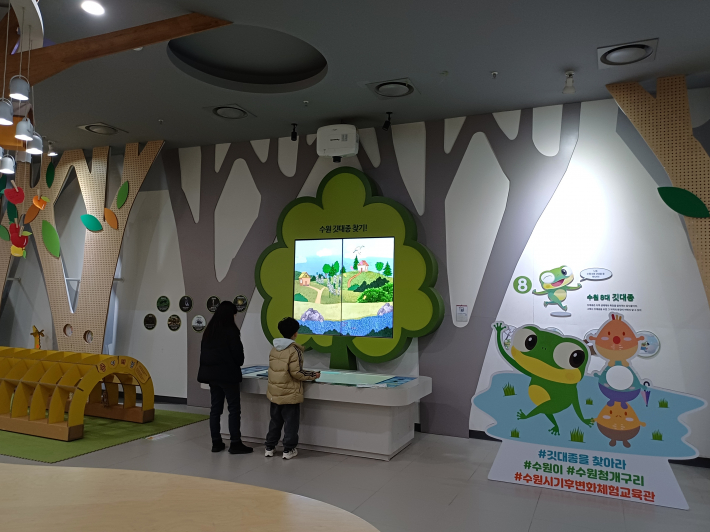 엄마와 초등학생이 블록 8가지의 다양한 수원의 깃대종이가 화면에 나타나는 체험 모습