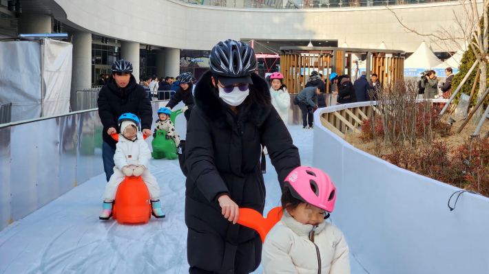 보호자와 함께 썰매를 타며 눈 놀이를 즐기는 아이들.