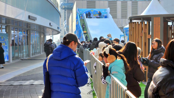 보호자와 함께 썰매를 타며 눈 놀이를 즐기는 아이들.