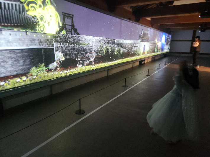 성곽 앞에서 움직이면, 몸짓에 따라 단청 문양과 꽆잎들이 화려하게 변한다.