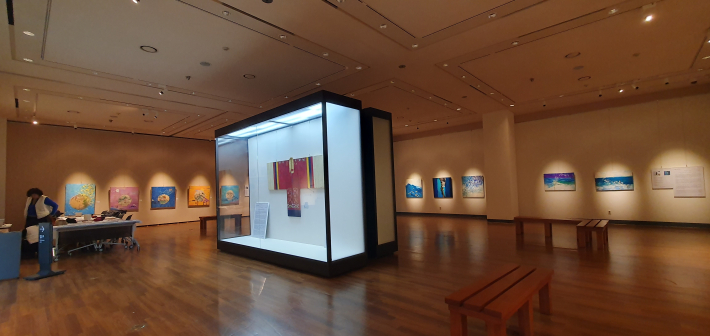 전시장 입구 정면에 설치된 강남철 작가의 붉은색 활옷 작품. 유리 쇼케이스 안에 전시되어 관람객을 맞이하고 있다.