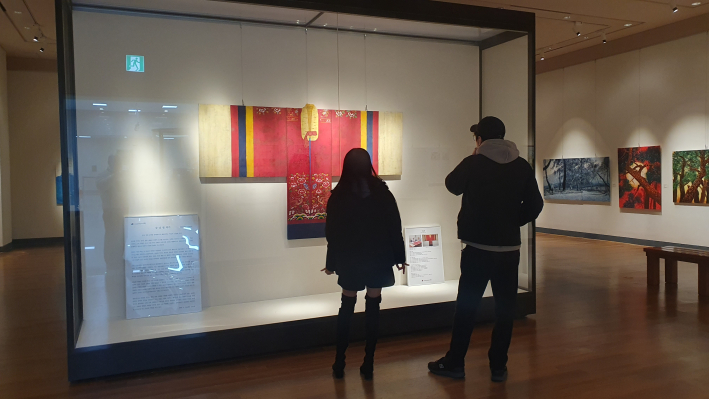 이번 전시를 기획하고 참여한 강남철 작가의 활옷 작품을 감상하는 관람객 모습.