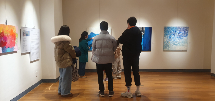 푸른 색채의 겹침을 통해 내면의 치유와 희망을 추상적으로 표현한 작품을 가리키며 소개하는 양은진 작가.