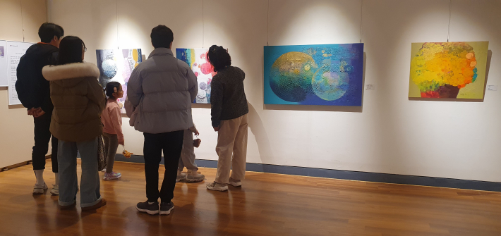 꽃과 빛의 이미지를 통해 삶의 환희와 기쁨을 밝은 색채로 표현한 자신의 추상화 작품 앞에 선 박정일 작가.