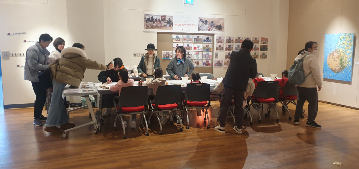 전시장 한편에 마련된 체험 공간에서 관람객들이 '수원화성 그리기' 프로그램에 참여하여 그림을 그리고 있는 모습.
