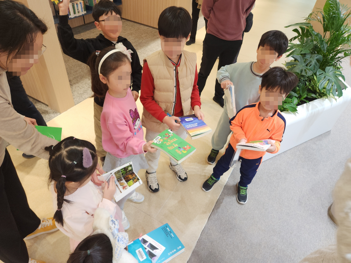 도서관에서 아이와 부모가 함께 기후 관련 관심 있는 책을 골라보았다.