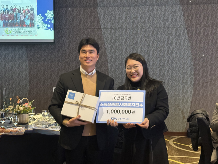 좌측에 수원시약사회 회원약국 관계자와 우측에 능실종합사회복지관 김소영 부장이 전달식 피켓을 들고 나란히 사진을 찍고 있다. 