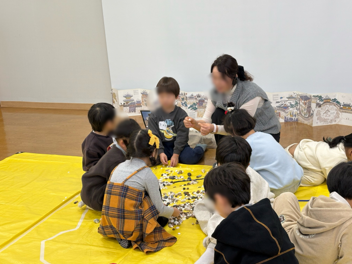 다양한 돌을 만지며 탐색 놀이에 참여하는 아이들 모습