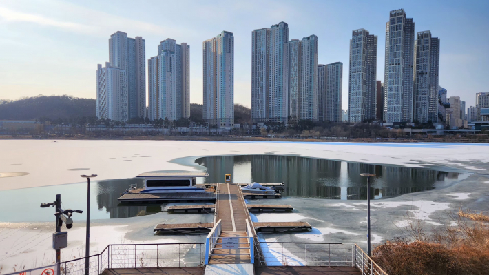 꽁꽁 언 호수 위로 따스한 햇살이 내리쬐는 광교호수공원의 전경.