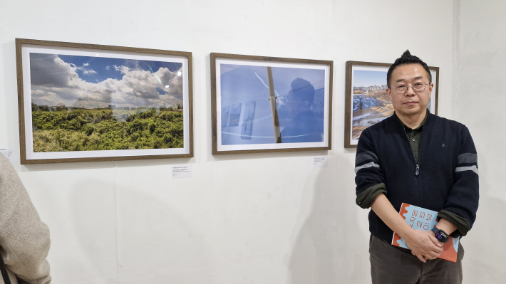 경기도의 구석 구석을 누비고 다니면서 사진을 찍은 박김형준 작가가 사진 앞에 서 있다 