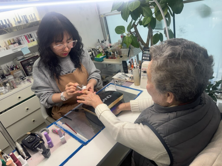 홀로 사는 어르신이 말자네일에서 네일아트를 받으며 이야기를 나누고 있다.   