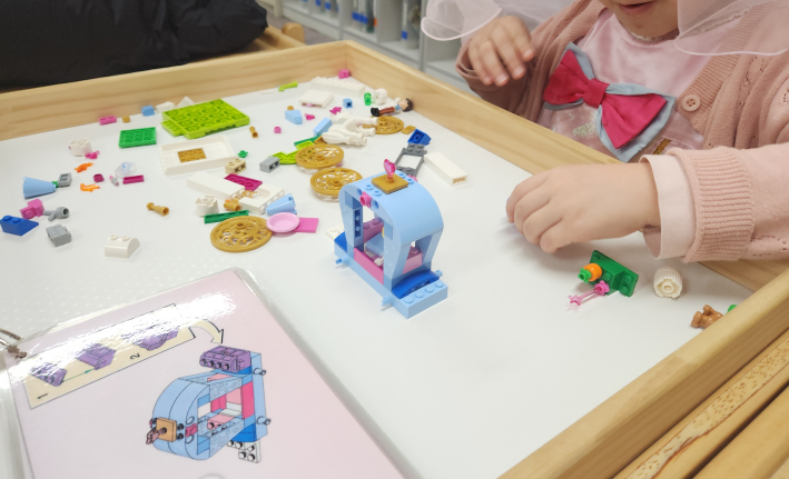 설명서를 펼쳐 들고 블럭 조립에 집중하는 아이의 모습