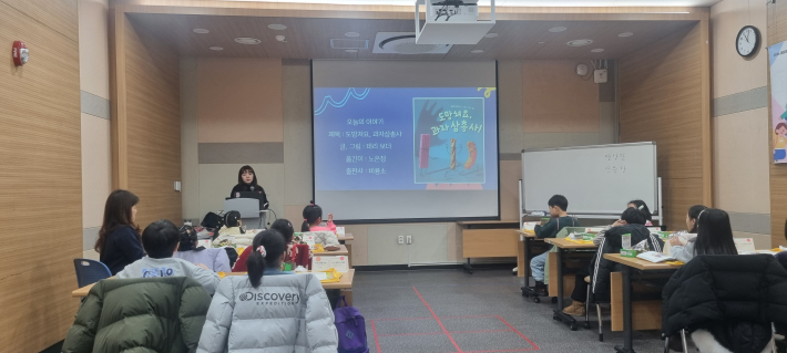 도망쳐요, 과자 삼총사! 오늘의 그림책 소개를 동화 구연하고 있다. 