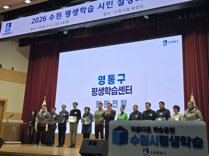 동 평생학습센터 현판 전달식에서 관계자들이 무대에 올라 기념 촬영을 하고 있다.