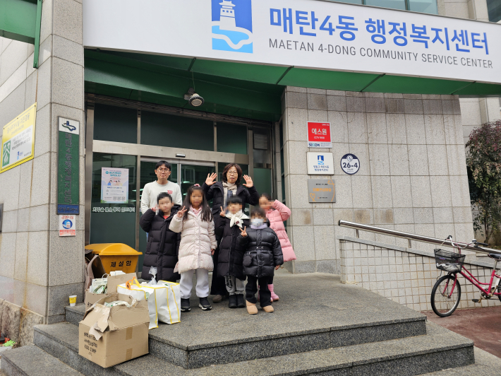 중앙어린이집 원아들과 교사가 매탄4동 행정복지센터에 우유팩을 전달하고 있다.