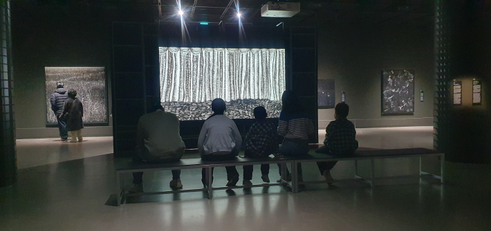 시장 내 마련된 의자에 앉아 영상 작품을 감상하며 잠시 휴식을 취하는 관람객들