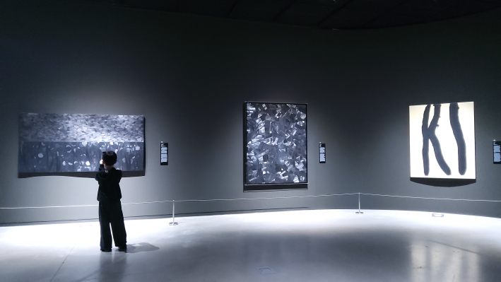 흑백의 강렬한 대비가 느껴지는 작품 앞에 멈춰 서서 몰입하고 있는 어린이 관람객