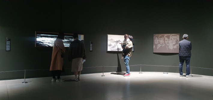 한 아버지가 아이를 안고 작품 옆 상세 설명문을 함께 읽으며 감상에 젖어 있는 모습