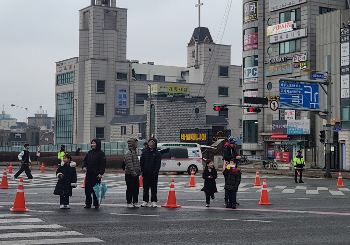 수원 성균관대역 부근에서 시민들이 도로 옆에 모여 마라톤 참가자들을 응원하고 있다. 어린이와 가족 단위 관람객들이 손을 흔들며 선수들을 격려해 생활체육 축제 분위기를 더했다.