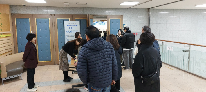 관객들이 줄서서 음악회장인 강당으로 입장하고 있다.