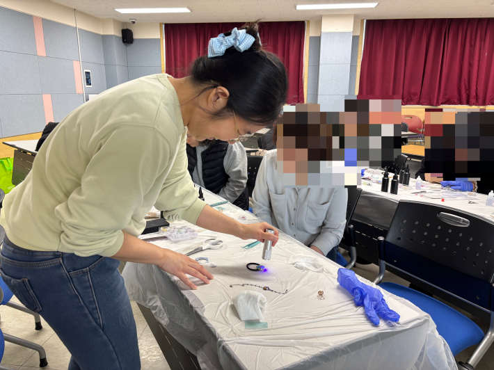 강사가 램프를 들고 책상에 놓인 레진아트를 비추는 중