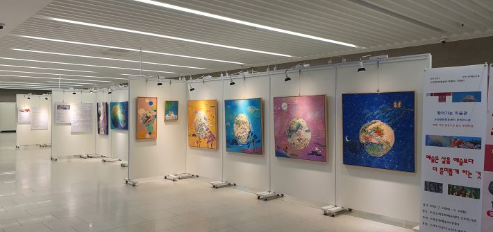 전시장 우측에 배치된 현대적 회화 작품들과 안내 배너의 모습