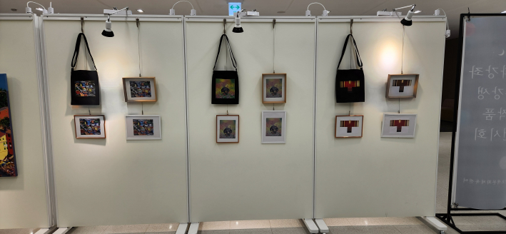 에코백과 액자 형태의 프린트 등 생활용품 전시가 이어지는 가벽의 오른쪽 모습