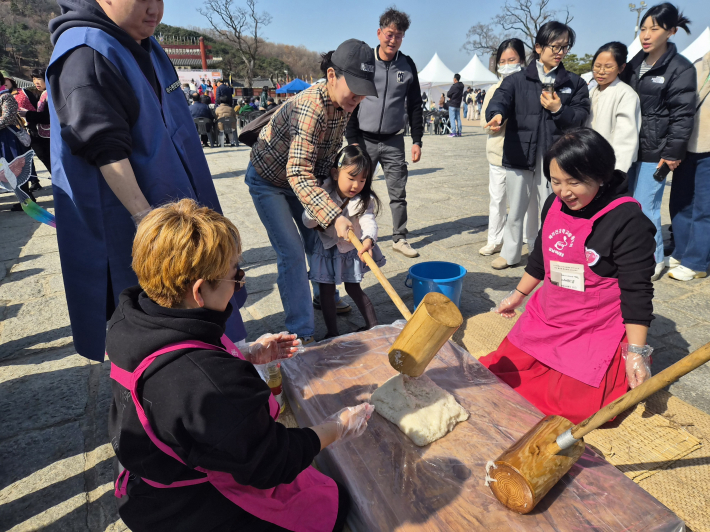 헤라건강학교총동문회 회원들이 떡을 뒤집으면 시민들이 힘차게 떡메를 내리치며 즐거워하고있다