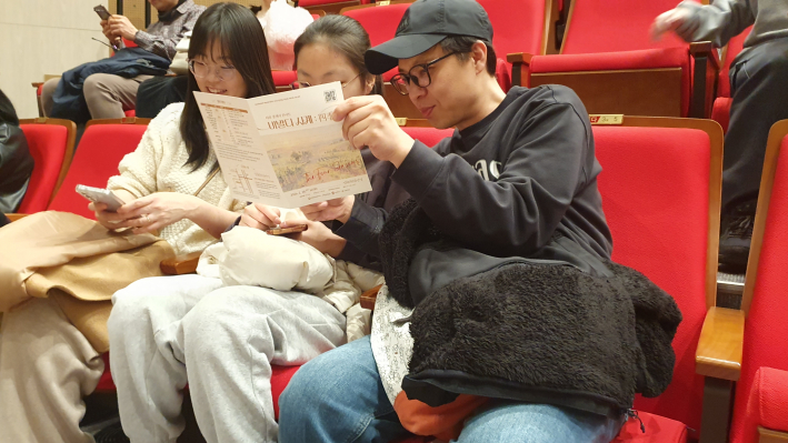 객석에 앉아 공연 안내 리플릿을 살펴보고 있는 임연철 관람객 가족