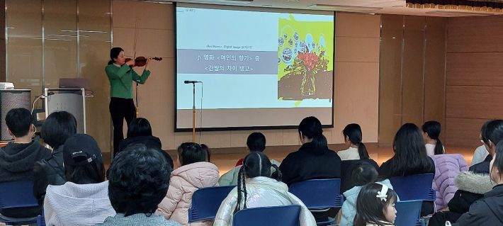 이수민 작가가 클래식 음악과 미술을 접목한 특강을 하면서 바이올린 연주를 하고 있다.