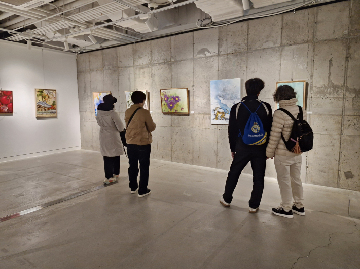 관람객들이 작품 앞에서 색의 흐름과 붓의 흔적을 천천히 따라가며 감상하고 있다.