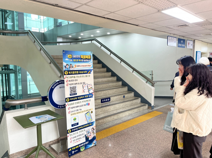 수원시 공직자들이 직원복지통합플랫폼, 인공지능 챗봇 등을 안내하는 홍보물을 보고 있다.     