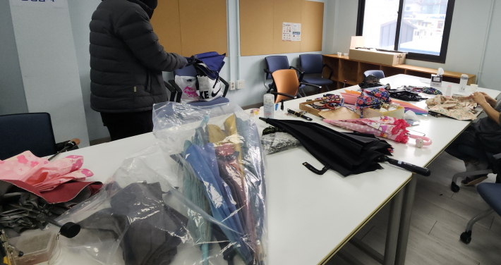 시민들이 가져온 다양한 우산들이 수리 접수를 기다리며 접수대에 놓여 있다.