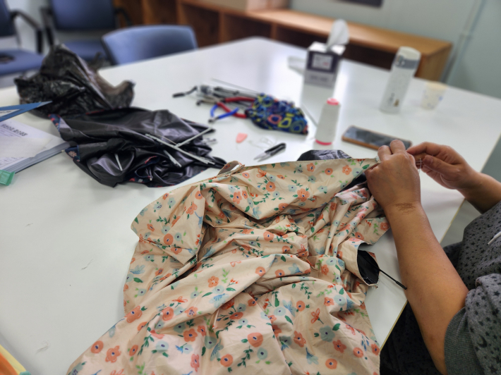 수리 작업대에서 찢어진 우산을 정비하며 다시 사용할 수 있도록 고치고 있다.