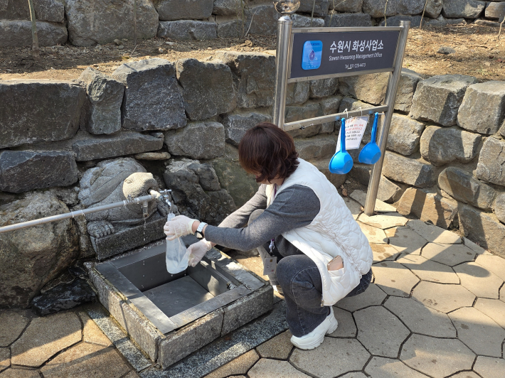 부서 관계자가 팔달 약수터에서 수질검사 의뢰용 물을 채취하는 사진