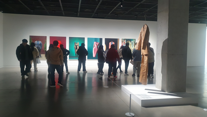 안창홍이 화려한 색채를 배경으로 알맹이 없는 빈 옷을 그려낸 회화 연작 〈유령패션〉을 관람객들이 감상하는 모습