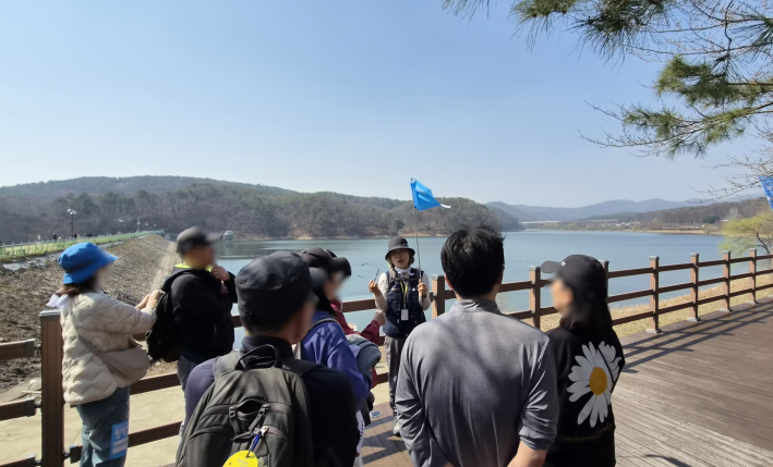 해설그룹이 광교저수지 앞에서 지게길과 모수길의 역사를 듣고 있다.