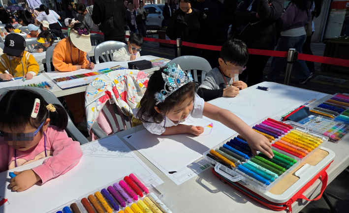 행리단길 차 없는 거리에서 테이블에 앉아 그림을 그리고 있는 어린이들