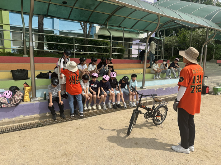 학교 운동장에서 학생들이 자전거 보호장구 착용 요령 교육을 받고 있다.     