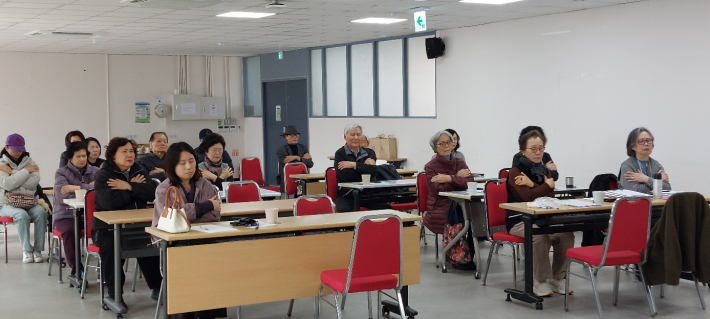 참여자들이 자리에 앉아 가슴에 손을 얹고 기공 치유 프로그램에 참여하며 심신 안정을 돕는 시간을 갖고 있다.