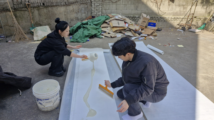 경희대학교 쿠키(HKU-KEY) 봉사 동아리 단원들이 벽지에 풀칠하는 모습(밤밭 노인복지관 제공)